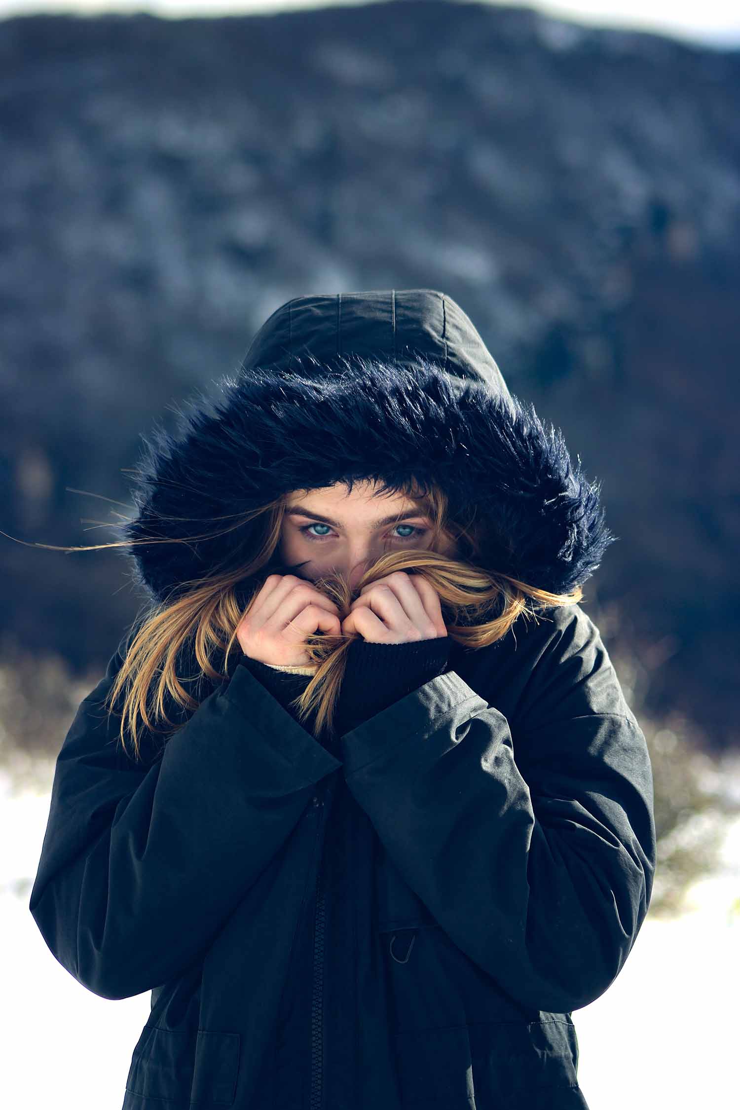 a person in a black coat with a hood covering her face